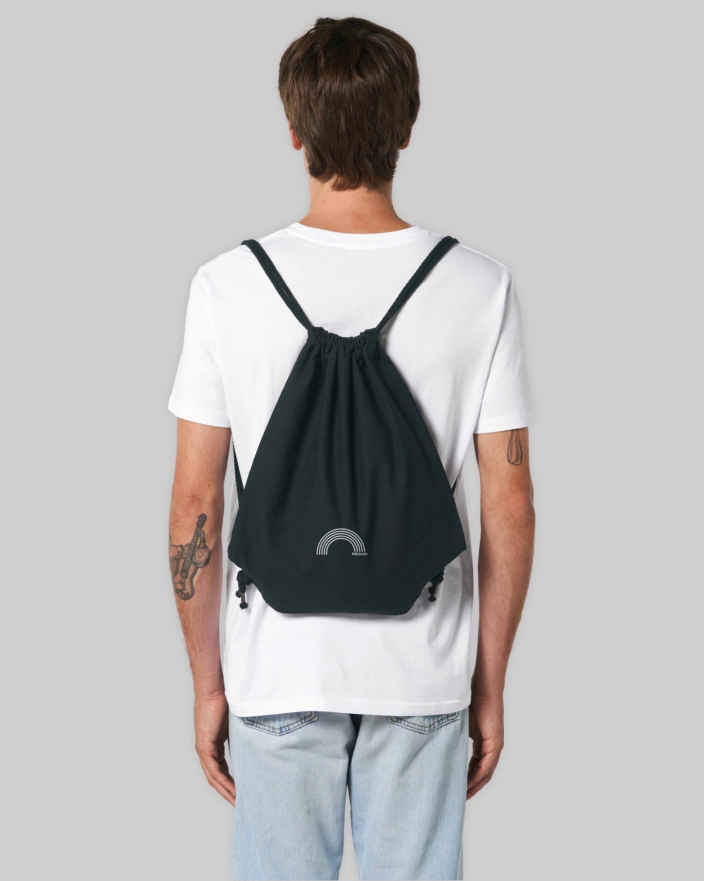 EINHORST® Sportbeutel in "Schwarz" mit dem Motiv "proud Regenbogen" in der Kombination weißer Regenbogen mit weißer Schrift, Bild von männlicher Person mit Sportbeutel