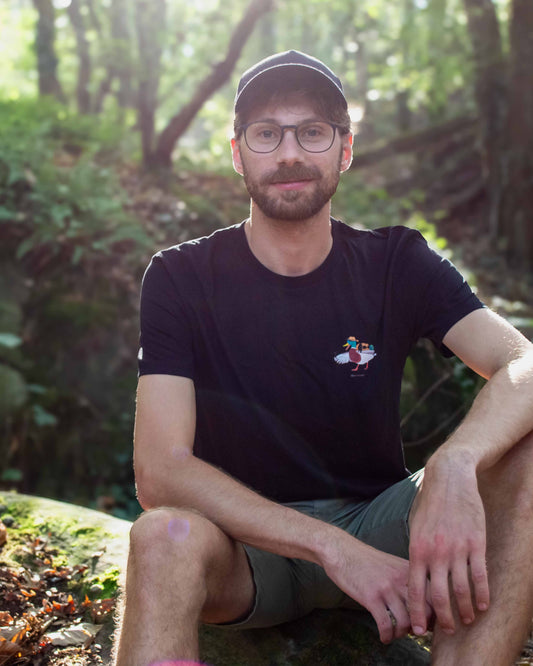 EINHORST® unisex Organic Shirt in Schwarz mit dem Motiv "Abenteuer", Bild von männlicher Person mit Shirt draußen