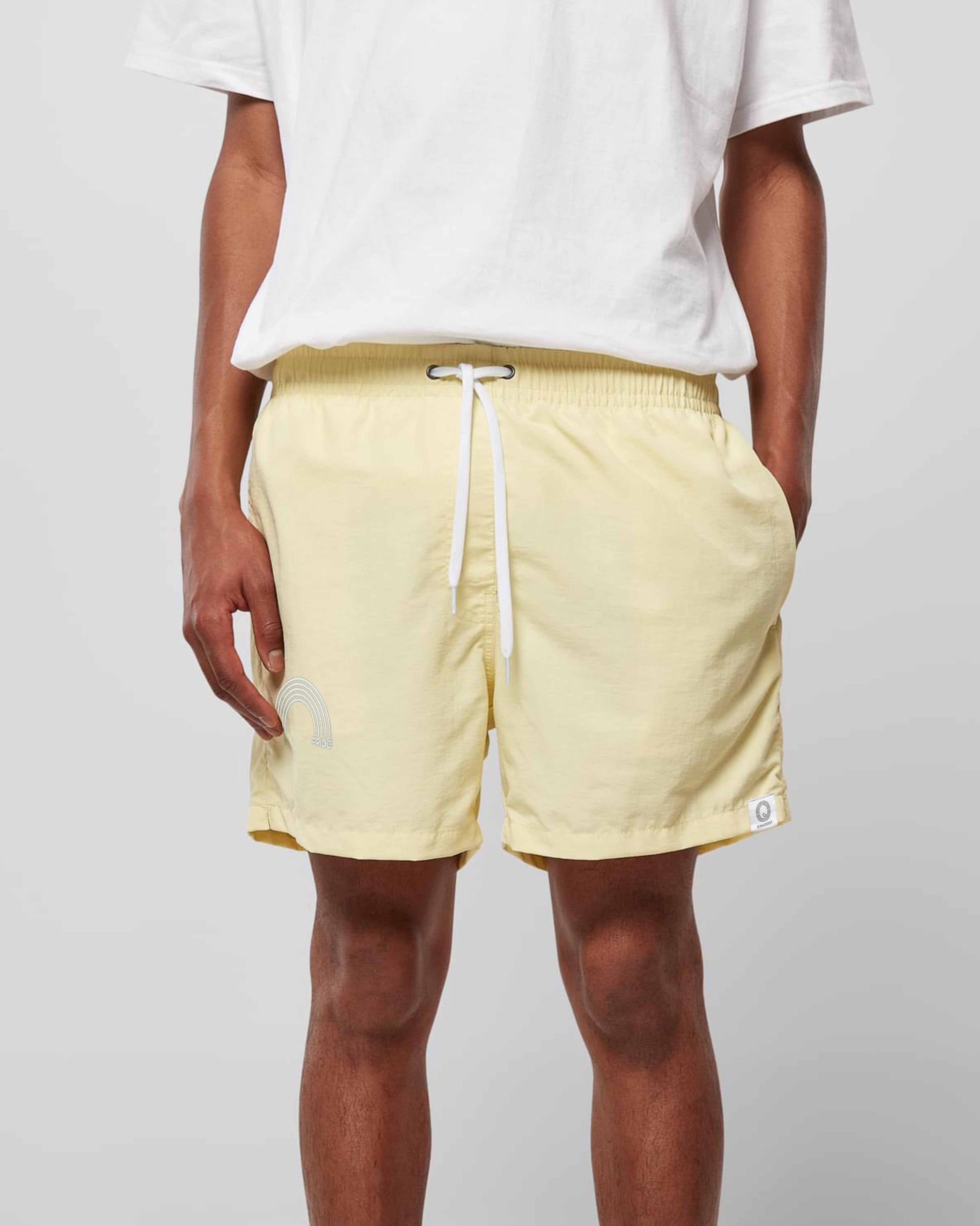 EINHORST® Schwimm- & Sportshorts mit dem Motiv "pride-Regenbogen" in der Farbe "Soft Yellow", Bild von einer männlichen Person von vorne, die die Shorts trägt